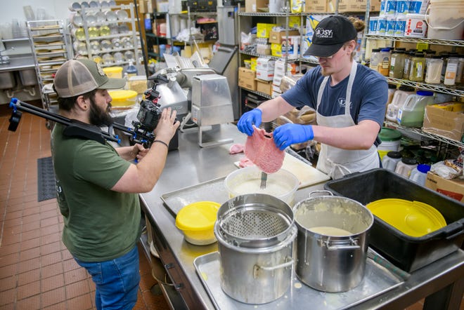 Videographer Michael Dick, left, records Busy Corner restaurant employee Brady Lenover preparing a tenderloin Wednesday, March 13, 2024 in Goodfield for an episode of the "America's Best Restaurants" web show.
