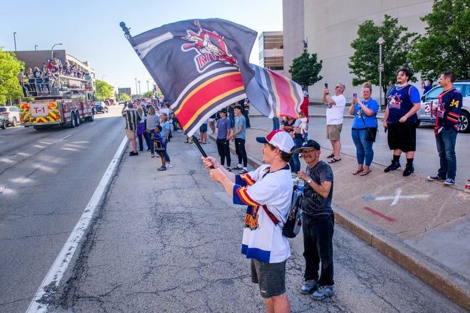 Peoria Rivermen fans celebrate as the team drives by atop a Peoria Fire Department ladder truck during a public celebration for their SPHL President's Cup hockey championship Friday, May 3, 2024 at the Peoria Civic Center.